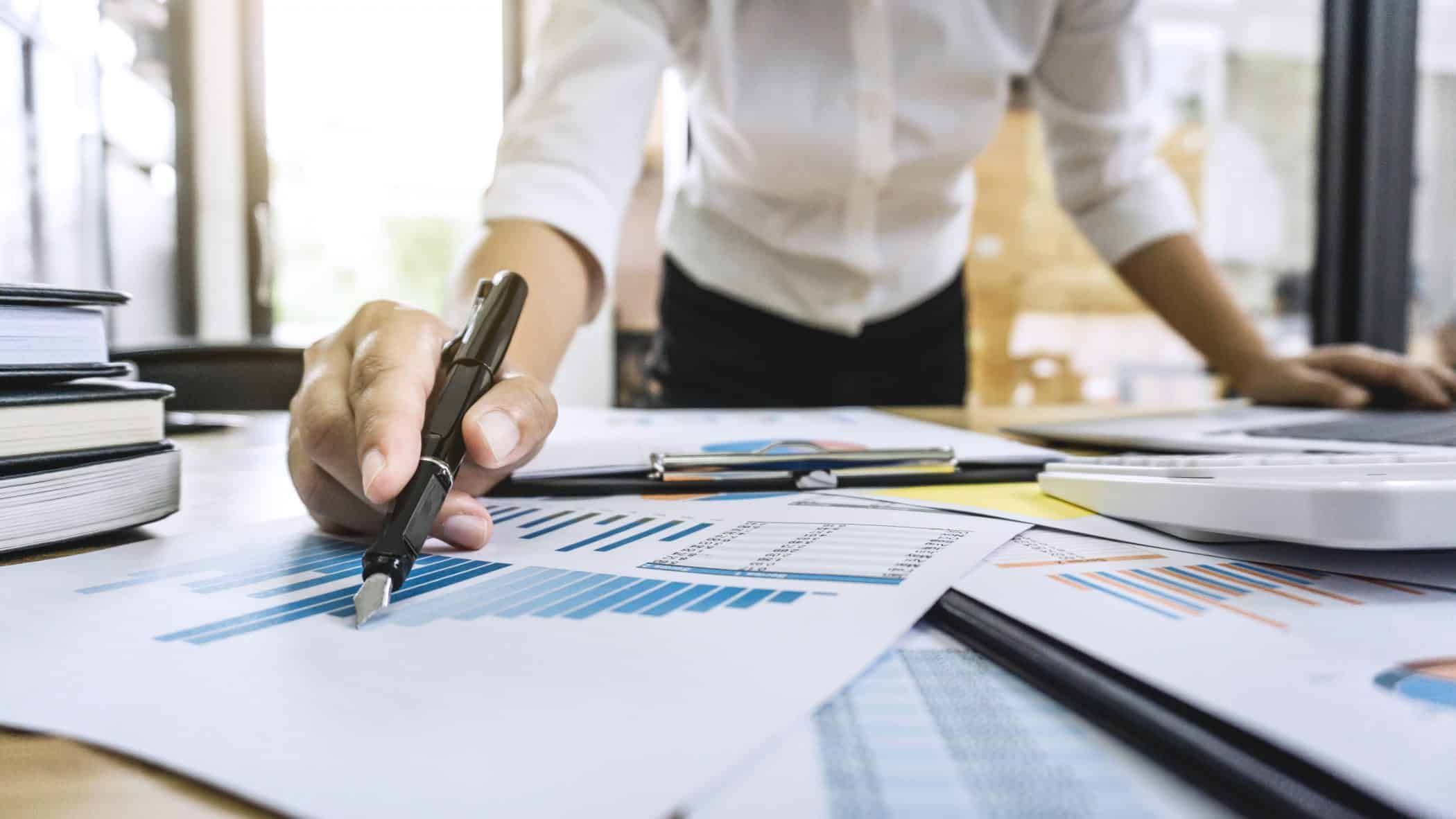 Business woman accountant working and calculating financial data on graph documents, doing finance in workstation.