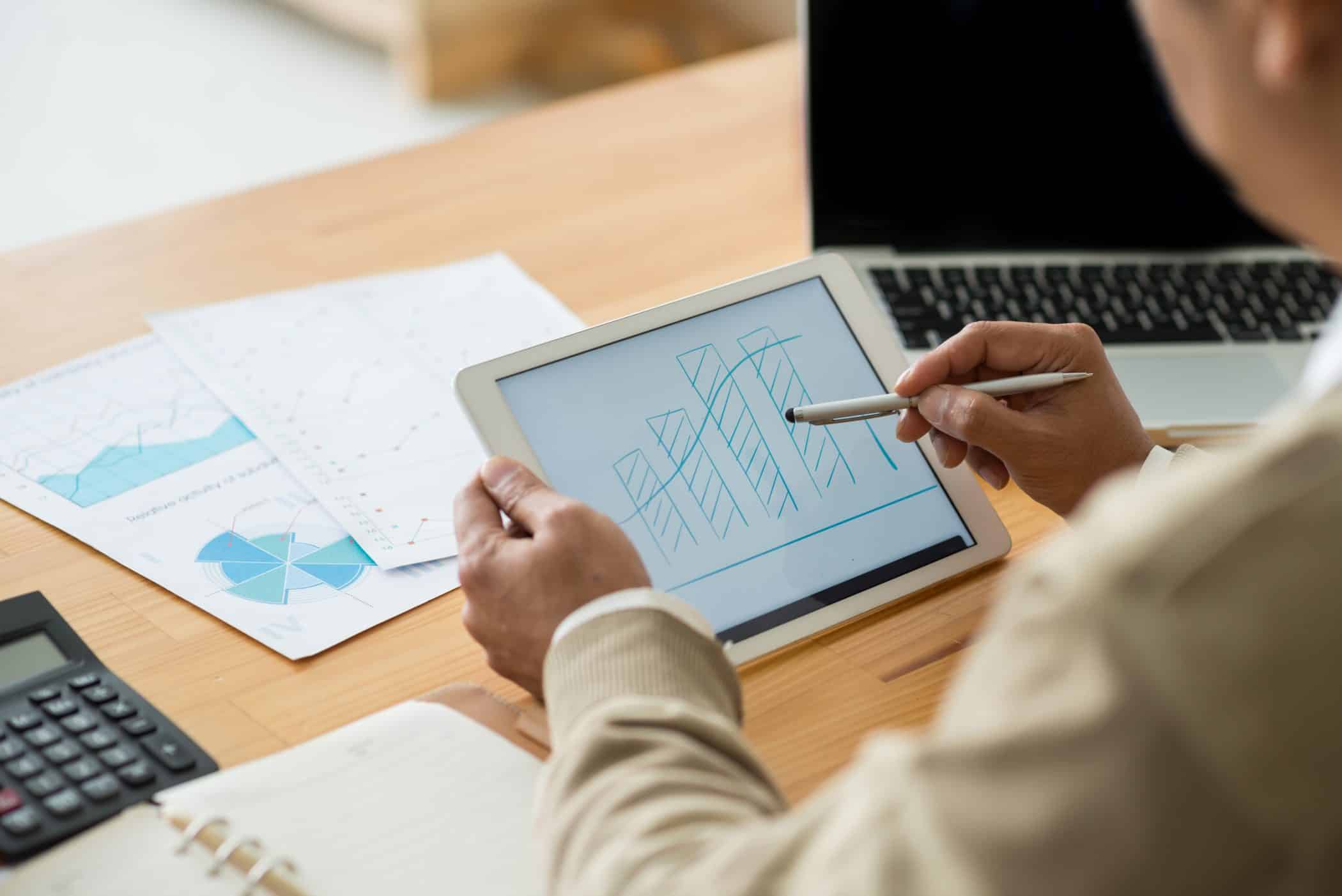Financial manager examining bar diagram on the digital tablet, view over the shoulder