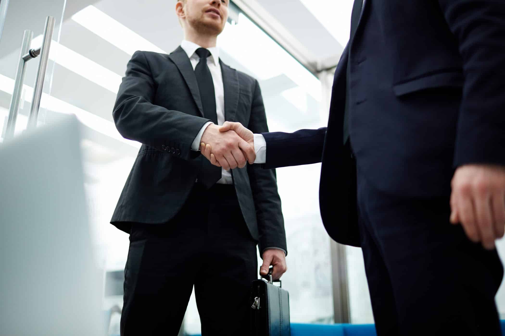 Businessmen in suits handshaking after meeting